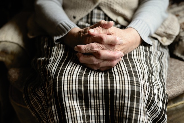 Close up of a woman with her hands in her lap.