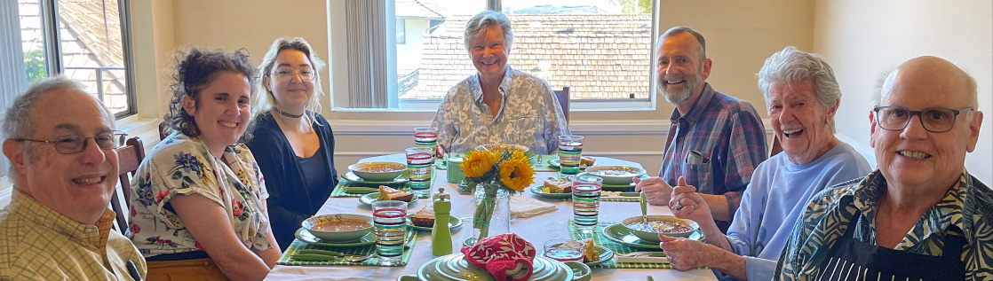 a group of older adults and two younger women smiling around a table