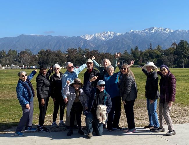 a group of older adults standing pointing at mountains in the background