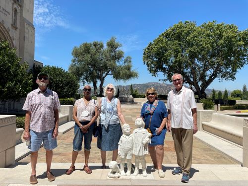 a group of older adults wearing sunglasses standing next to a statue