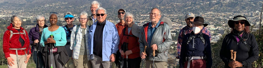 a group of older adults standing on top of a hill overlooking Los Angles smiling