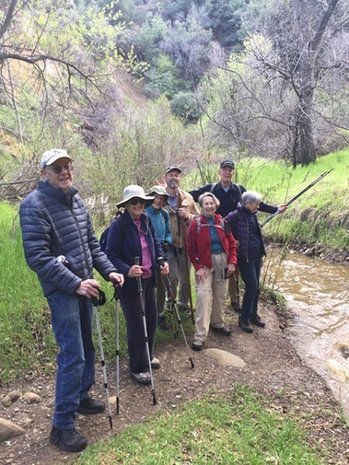 a group of older adults smiling next to a small river
