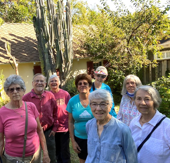 group of older adults smiling with trees and cactus in the background